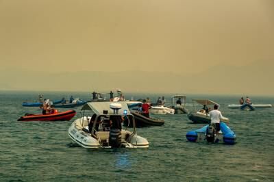 People are evacuated by boat as they flee a fire burning near the Greek town of Nea Anchialos. EPA 
