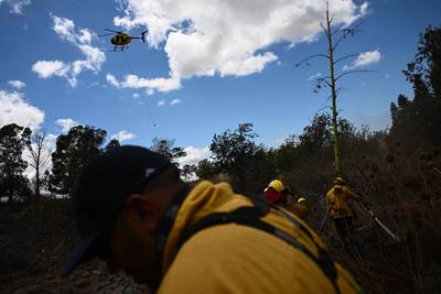 A helicopter drops supplies as Maui County firefighters extinguish a blaze near homes in Kula, Hawaii. AFP