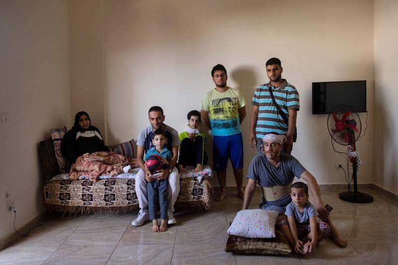 The family of Ali Kinno pose for a photograph at a temporary apartment in the coastal town of Jiyeh, south of Beirut, Lebanon, on September 15, 2020. The Kinno family from Syria's Aleppo region was devastated in the wake of the August 4 explosion at the Beirut port, their tragic story reflects the particular pain of Syrian refugee families in Lebanon, which is now home to about a million Syrians. Hassan Ammar / AP