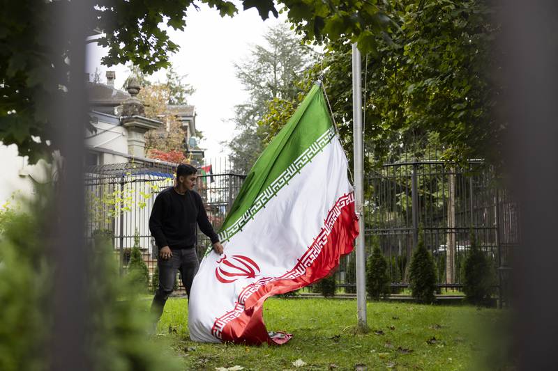 A protester takes down the Iranian flag on the grounds of the Iranian embassy in Bern, Switzerland. AP