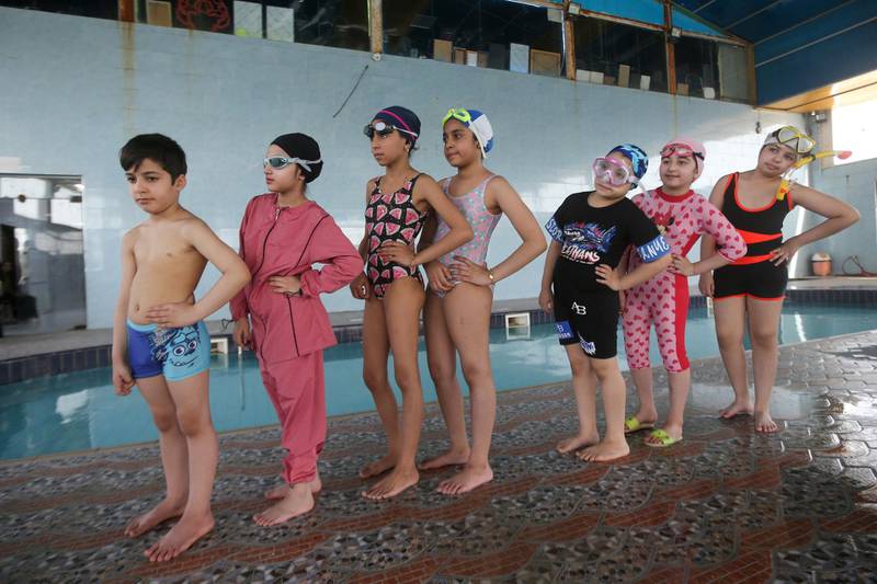 Young swimmers stand in line before entering the pool for their lesson in Basra. Reuters