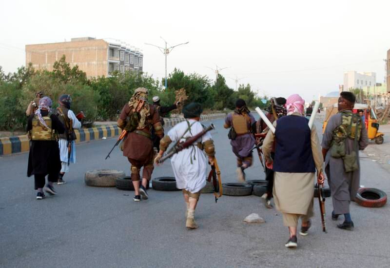 Militia members make their way through the city of Herat. AP