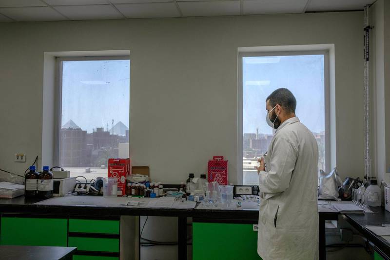 A lab technician works at the Eva Pharma facility in Cairo, Egypt, with the Giza Pyramids seen from the window. AP Photo