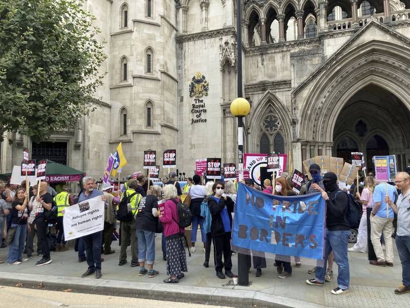 Demonstrators stand outside the Royal Courts of Justice in London, protesting against the UK government's plan to send some asylum seekers to Rwanda. PA via AP