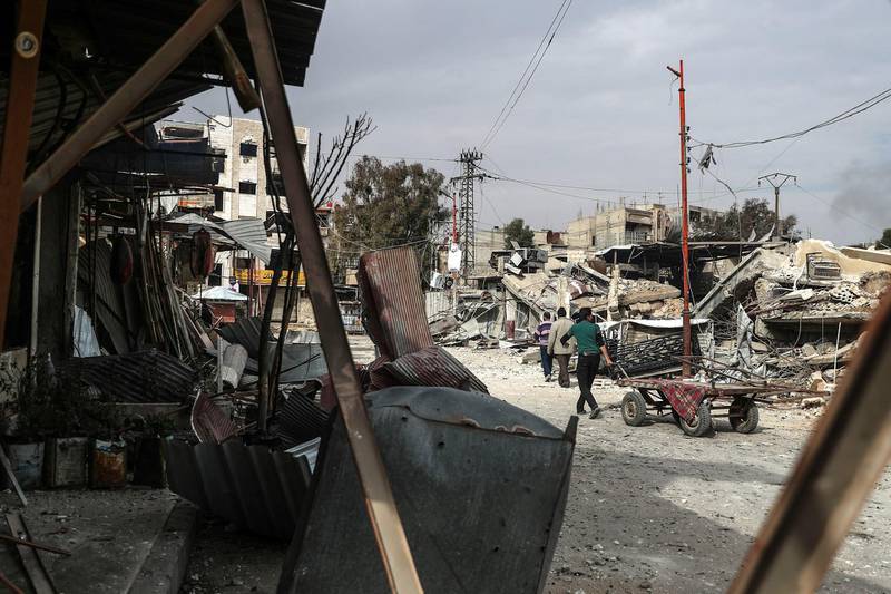 People walk next to destroyed buildings from an alleged barrel bomb attack, at rebel-held Douma, Syria. Mohammed Badra / EPA