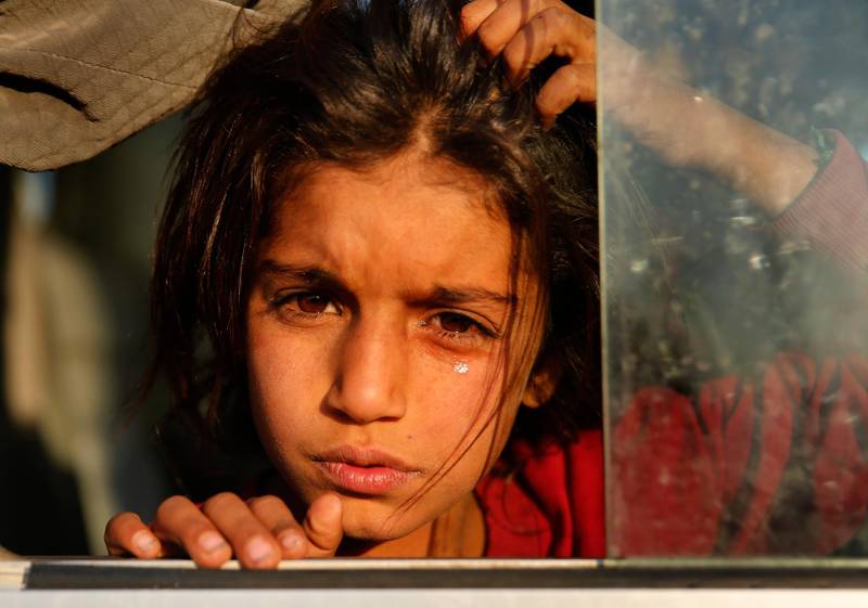 A Syrian girl who is newly displaced by the Turkish military operation in northeastern Syria, weeps as she sits in a bus upon her arrival at the Bardarash camp, north of Mosul, Iraq, Wednesday, Oct. 16, 2019. The camp used to host Iraqis displaced from Mosul during the fight against the Islamic State group and was closed two years ago. The U.N. says more around 160,000 Syrians have been displaced since the Turkish operation started last week, most of them internally in Syria. (AP Photo/Hussein Malla)