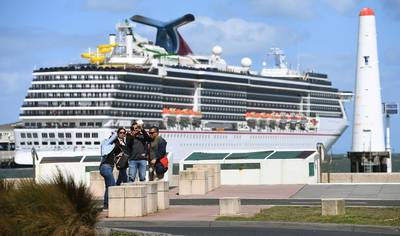 Tourists taking photos in front  of a cruise liner docked at Station Pier as Australian Prime Minister Scott Morrison on March 15 announces all cruise ships will be banned entirely from docking in Australia. AFP
