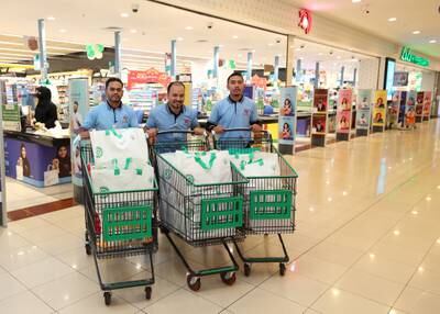 Supermarket staff pose for a photo with trolleys full of long-life bags.
