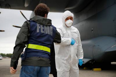 A Turkish military flight crew member, right, bumps elbows with a FEMA worker as crews unload a donation of medical supplies from Turkey, Tuesday, April 28, 2020, at Andrews Air Force Base, Md. The donation to help fight the new coronavirus in the United States included surgical masks, sanitizers and protective suits. (AP Photo/Patrick Semansky)