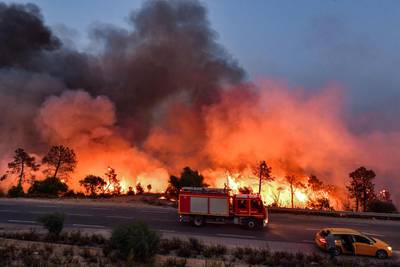 A fire engine moves along a road as a forest fire rages near the Tunisian town of Melloula, close to the border with Algeria. AFP
