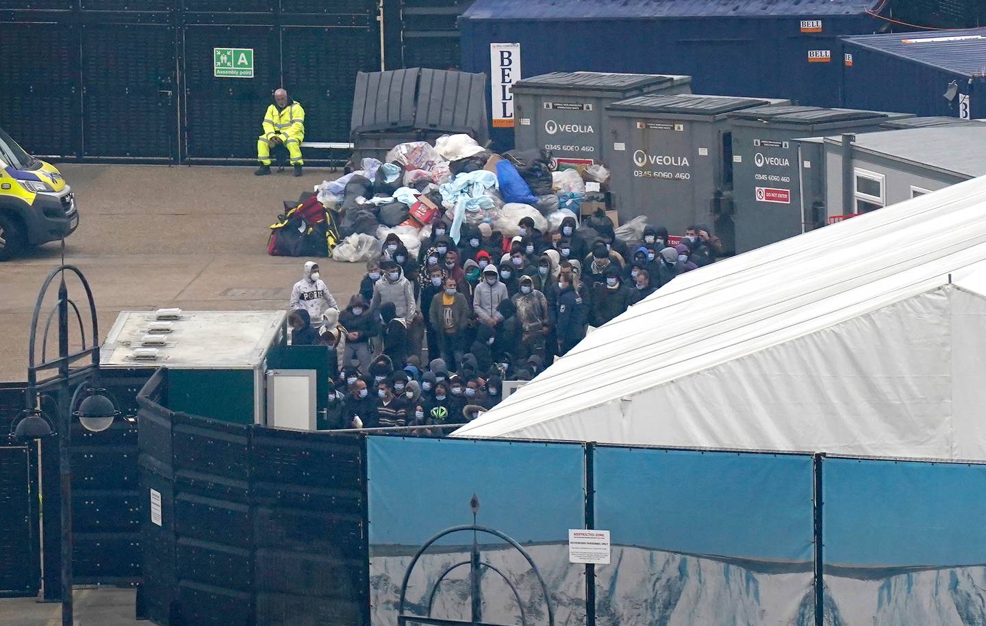 Migrants wait to be processed after being brought ashore in Dover, Kent, in south-east England, onboard a Border Force vessel. PA
