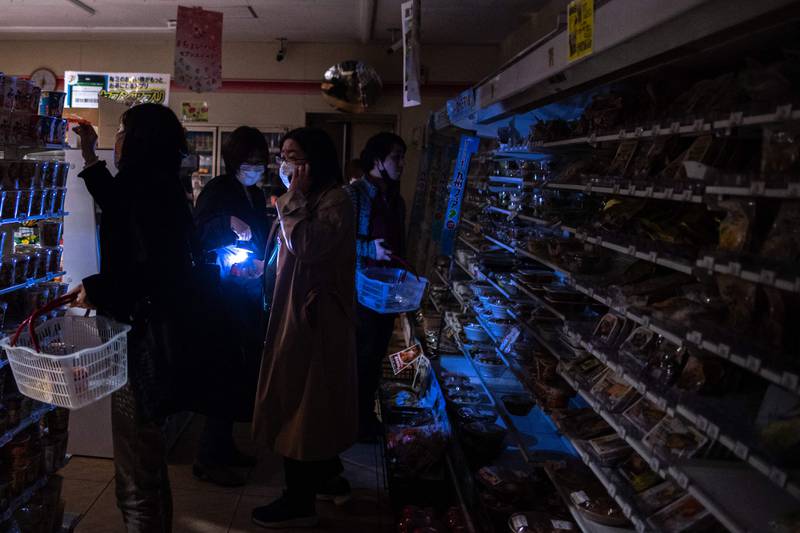 People shop in a residential area during a power cut in Koto district, Tokyo. AFP