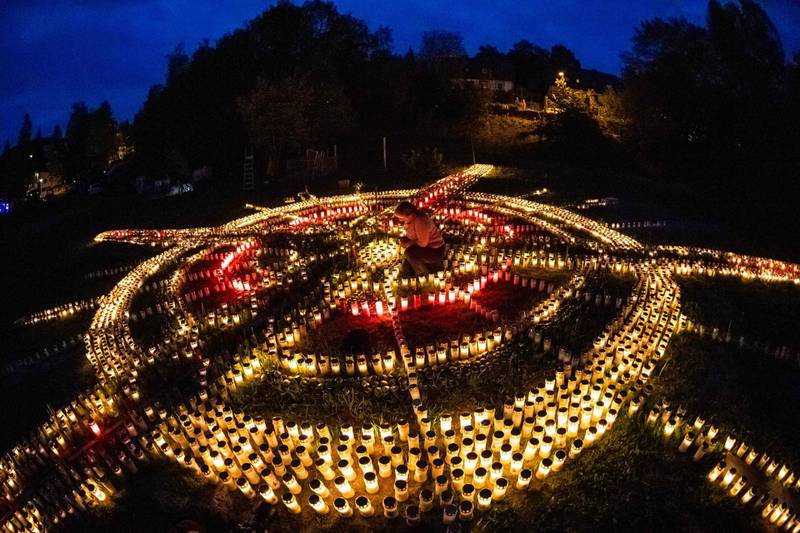 TOPSHOT - 60-year-old Gertrud Schop lights candles arranged in the shape of a cross, with one candle dedicated to each of the more than 8,000 German Covid-19-related victims, in Zella-Mehlis, eastern Germany on May 19, 2020, amid the novel coronavirus / COVID-19 pandemic. Schop is planning to continue the project until a vaccine against Covid-19 is available. / AFP / JENS SCHLUETER
