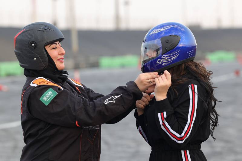 Almarglani helps a student to adjust her helmet. AFP