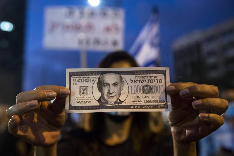 Israeli Protester holds a fake bill with  a photo of the Israeli Prime Minister Benjamin Netanyahu as she protests against the Government's economy response to the cororna virus crisis in Tel Aviv.  Getty Images