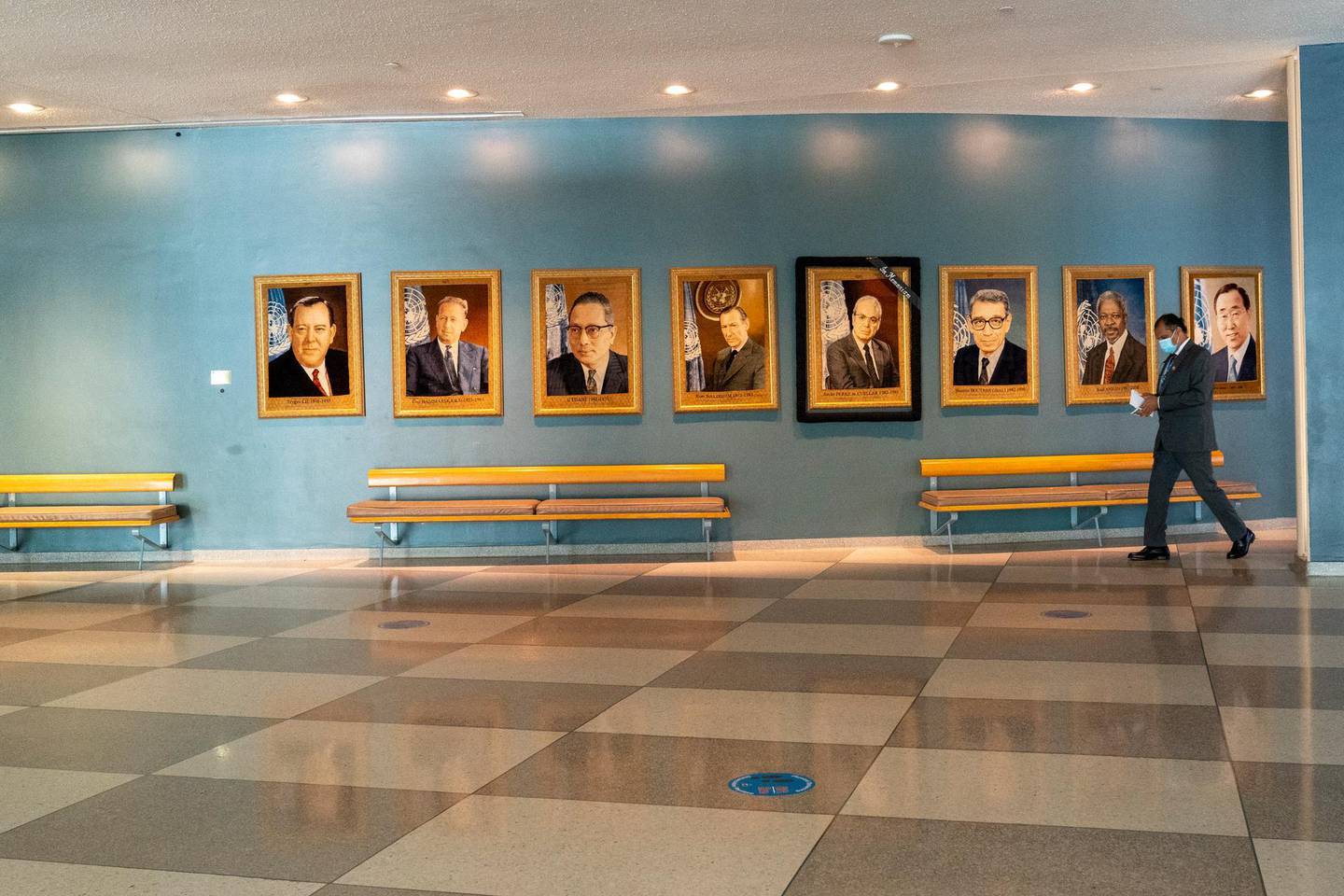 A man walk past portraits of former United Nations Secretary-Generals, Monday, Sept. 21, 2020 at United Nations headquarters. In 2020, which marks the 75th anniversary of the United Nations, the annual high-level meeting of world leaders around the U.N. General Assembly will be very different from years past because of the coronavirus pandemic. Leaders will not be traveling to the United Nations in New York for their addresses, which will be prerecorded. Most events related to the gathering will be held virtually. No access to world leaders on the U.N. grounds will be possible, therefore, and access to most anything will be extremely curtailed. (AP Photo/Mary Altaffer)