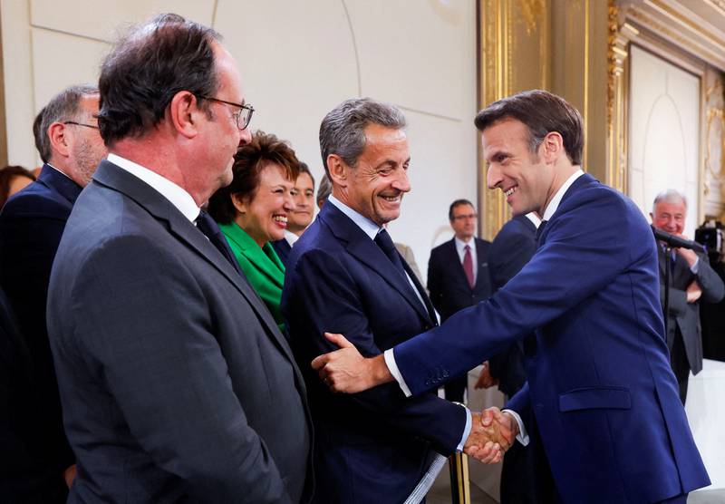 France's former president Francois Hollande, left, looks on as France's former president Nicolas Sarkozy shakes hands with Mr Macron. AFP