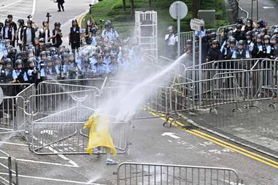 Police use a water canon on a lone protester. AFP