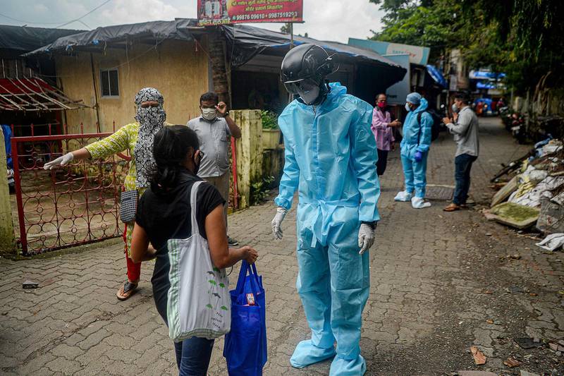 A volunteer health worker of the NGO Bharatiya Jain Sanghatana wearing personal protective equipment (PPE) using a smart helmet equipped with a thermo-scan sensor checks the body temperature of residents in Mumbai. AFP