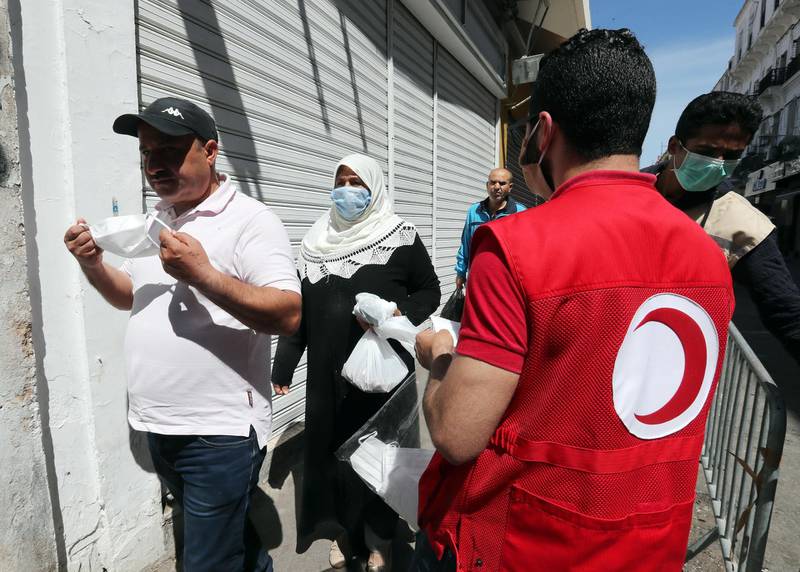 A Tunisian Red Crescent member distributes free masks in front of the central market in Tunis. EPA