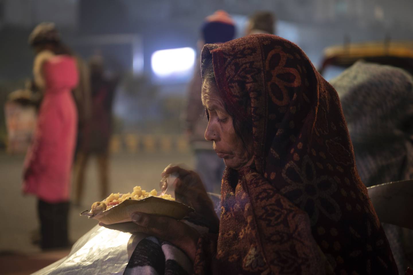 Une femme mange alors qu'elle s'installe pour la nuit à l'extérieur de l'hôpital.  Taniya Dutta / Le National