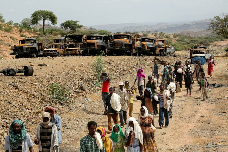 Villagers return from a market to Yechila town in south central Tigray, walking past scores of burned vehicles. Reuters
