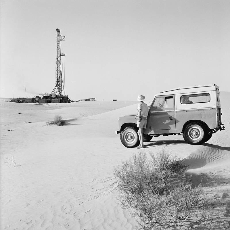 Deep in the desert, a worker with his Land Rover watches a drilling rig at the Murban Bab oil field in 1964. Photo: Adnoc