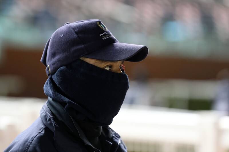 A security guard wraps up at a racing event in Dubai on January 28. Temperatures have dropped to single digits in the mornings and evenings. Chris Whiteoak / The National