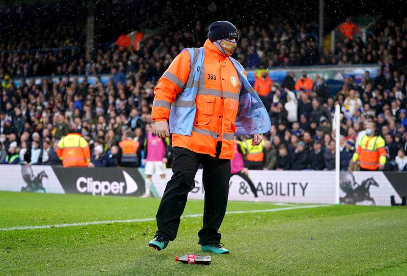 A match steward removes a bottle thrown on the pitch after it hit Burnley's Matthew Lowton at Elland Road on Sunday. PA
