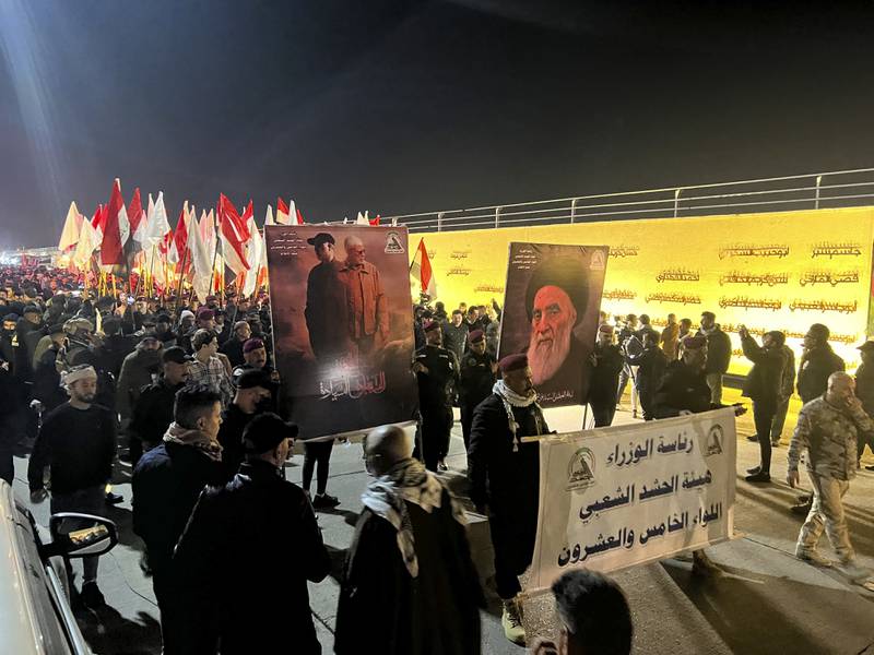 People hold photos of Abu Mahdi Al Muhandis, deputy commander of the Popular Mobilisation Forces, and Iranian general Qassem Suleimani in Baghdad, on Monday. AP