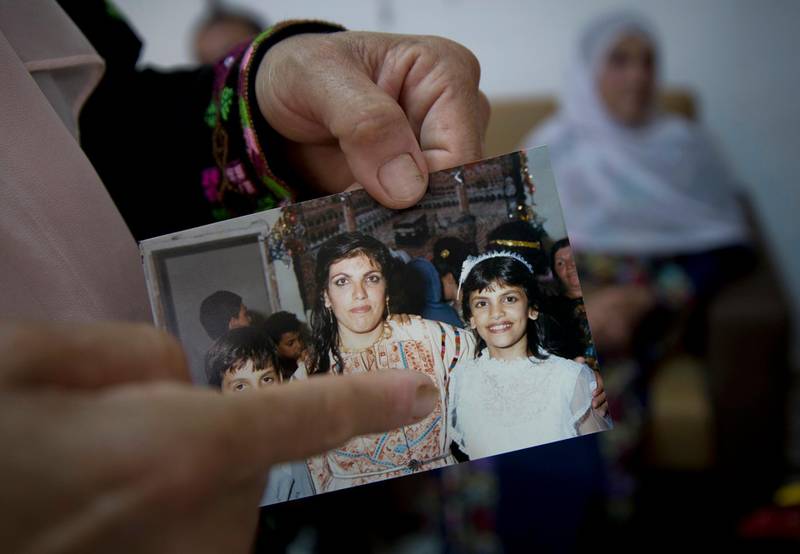 In this Wednesday, Aug. 8, 2018 photo, Fadwa Tlaib, an aunt of Rashida Tlaib points to a young Rashida in a 1987 picture with her mother Fatima and brother Nader, at the family house, in the West Bank village of Beit Ur al-Foqa. The Michigan primary victory of Tlaib, who is expected to become the first Muslim woman and Palestinian-American to serve in the U.S. Congress, is rippling across the Middle East. In the West Bank village where Tlaibâ€™s mother was born, residents are greeting the news with a mixture of pride and hope that she will take on a U.S. administration widely seen as hostile to the Palestinian cause. (AP Photo/Nasser Nasser)