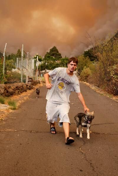 A man leads his dog away as a fire that started in Candelaria approaches. EPA