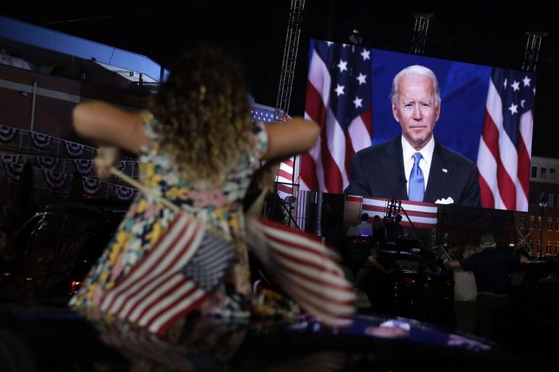 A supporter watches Joe Biden's acceptance speech from a parking lot outside Chase Center. AFP