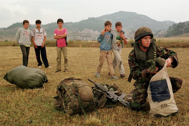 A UK paratrooper captures the attention of young Albanians after a parachute jump on August 17, 1998, during the Kosovo War. Getty