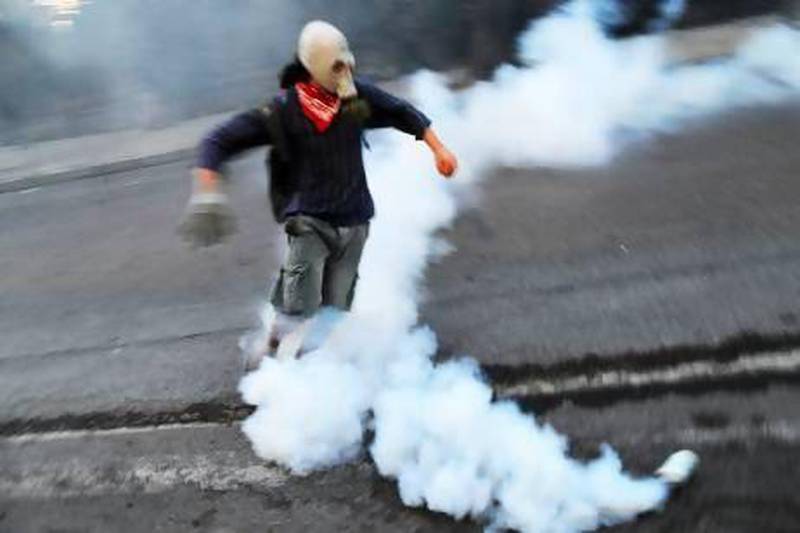 A Turkish protestor wearing a gas mask runs from a tear gas canister during clashes early on the morning of May 31, 2013 as part of a protest against the demolition of Taksim Gezi Park, in Taksim Square in Istanbul. Police reportedly used tear gas on early May 31 to disperse a group, who were standing guard in Gezi Parki to prevent the Istanbul Metropolitan Municipality from demolishing the last remaining green public space in the center of Istanbul as a part of a major Taksim renewal project. AFP PHOTO/BULENT KILIC