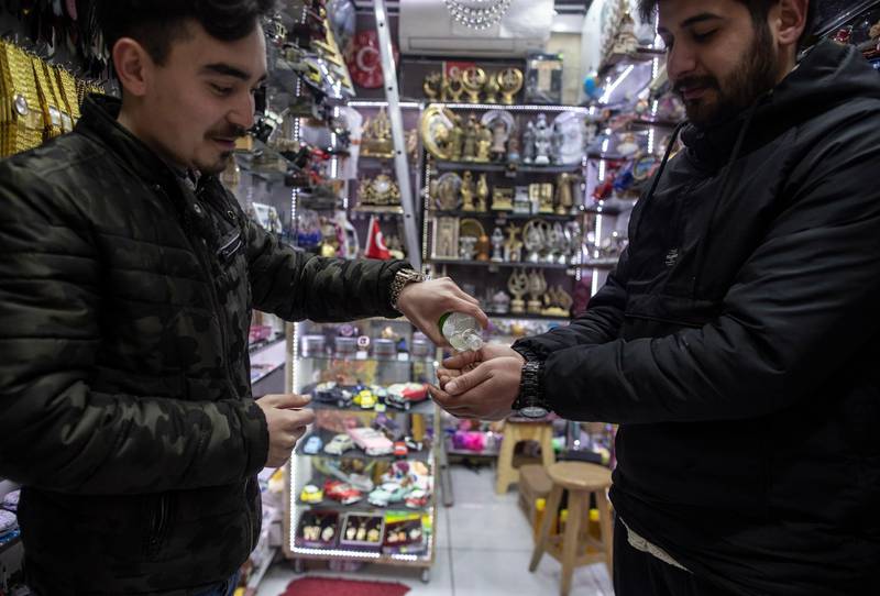 A shop owner offers perfume as a disinfectant to a customer at his shop in Istanbul, Turkey.  EPA