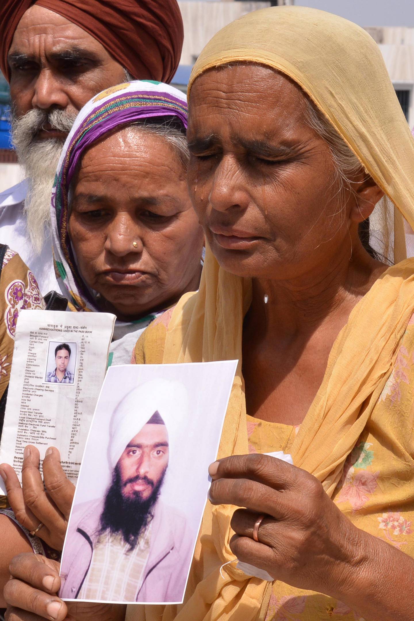 Relatives of Indian workers who were taken hostage in Iraq pose with photographs bearing their image during prayers for their release at the Gurdwara Baba Buddha Sahib at the village of Katthu Nangal, some 20 kms from Amritsar on June 24, 2014. India announced it would stop granting its nationals permission to travel to Iraq for work as it stepped up efforts to secure the release of 39 Indians abducted by gunmen. AFP PHOTO/NARINDER NANU / AFP PHOTO / NARINDER NANU