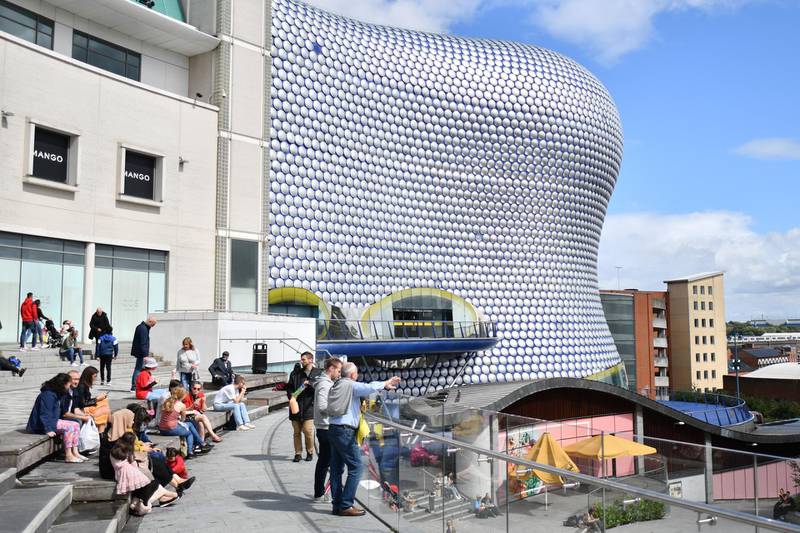 People sit outside the Bullring shopping centre in Birmingham, central England on August 22, 2020, as Britain's second-city, home to more than one million people, was made an "area of enhanced support", because of concern about a spike in cases of the novel coronavirus. (Photo by JUSTIN TALLIS / AFP)