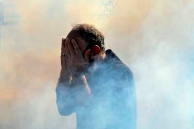 A retired member of the Lebanese security forces reacts as riot police fire gas canisters. EPA 
