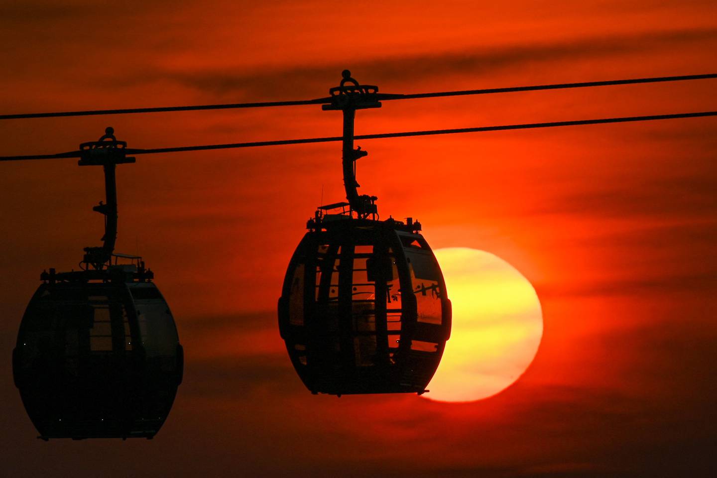 The sun sets behind cable cars in Singapore on October 15, 2021. AFP
