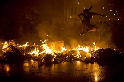 A demonstrator with his face covered jumps over a burning barricade during a march in support of teachers on strike in Rio de Janeiro. Felipe Dana / AP 