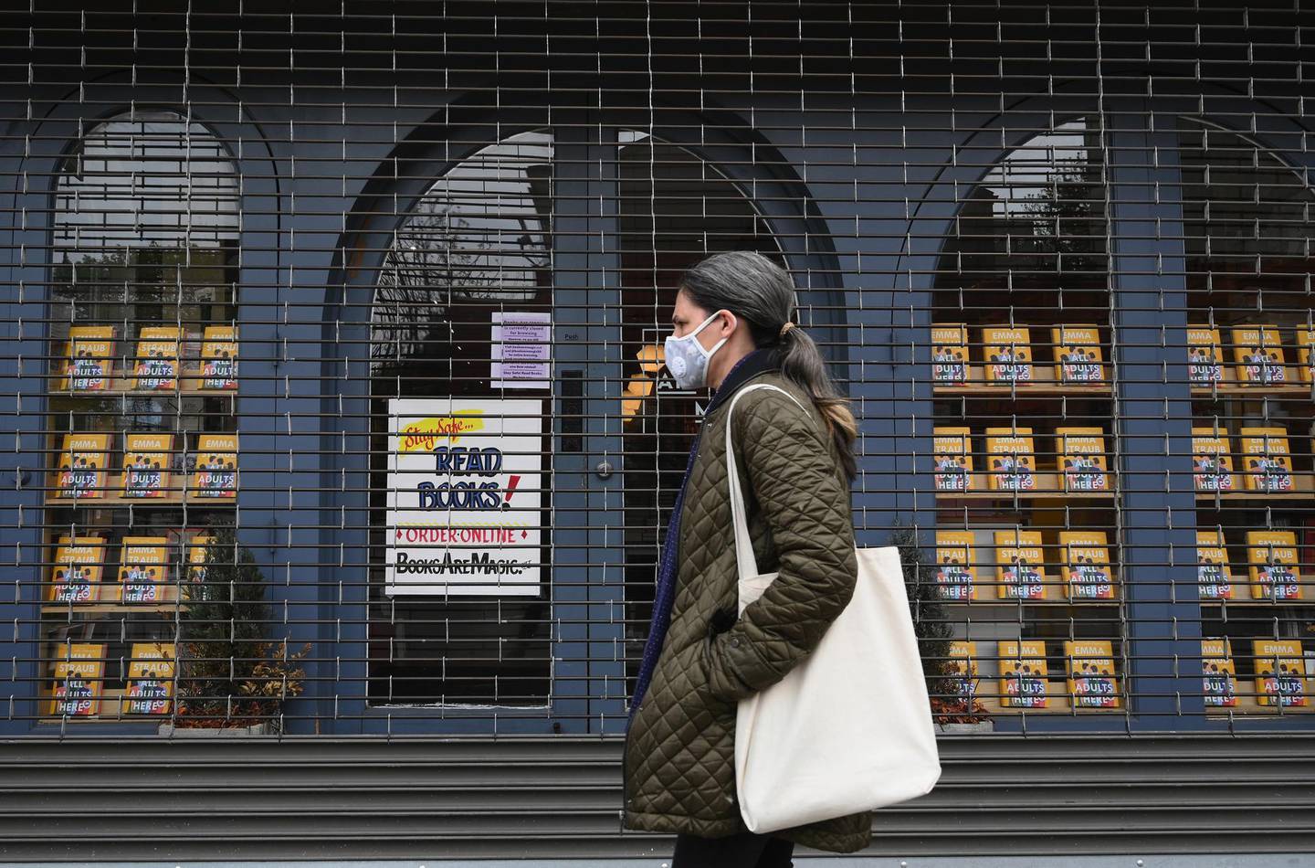 A woman walks by the closed "Books Are Magic" bookstore on May 5, 2020 in the Brooklyn borough of New York City. (Photo by Angela Weiss / AFP)