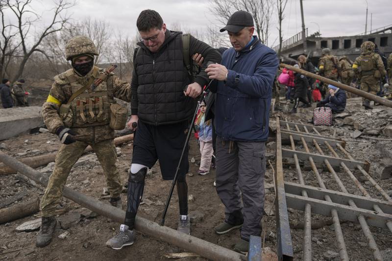 A man is supported after crossing the Irpin river while fleeing the town of Irpin, Ukraine. AP