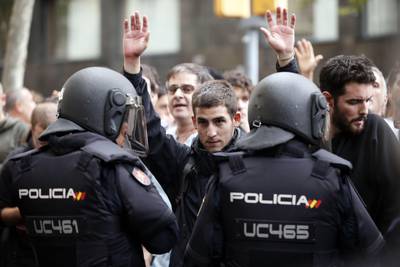 A man raises his arms in front of Spanish police after the seizure of ballot boxes in a polling station in Barcelona, Spain. Pau Barrena / AFP Photo