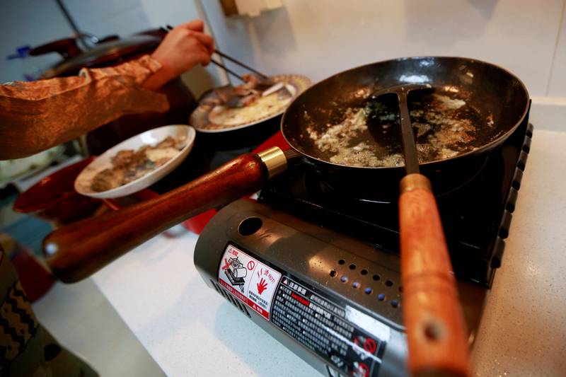 Fu Liting prepares to cook fish in a wok at her house in Beijing. Reuters