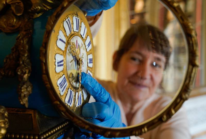 Goodwood's clock curator Su Fullwood adjusts the hands on a Sevres ormolu French mantel clock on Thursday, at Goodwood House in Chichester, as she prepares the antique collection for British Summer Time, which starts on Sunday March 27. PA
