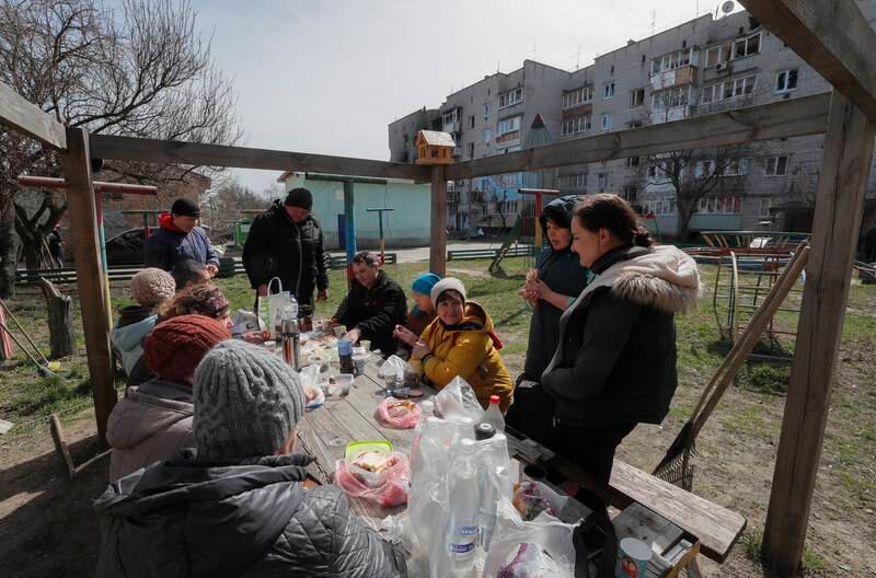 Residents who cleared debris after Russian shelling eat lunch outside a damaged building in Makariv, near Kyiv. EPA
