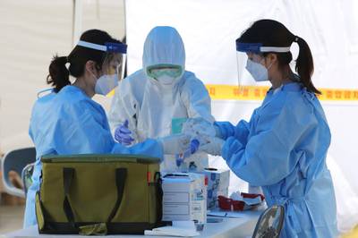 Health officials gather samples taken from people during the Covid-19 testing at a makeshift clinic in Seoul, South Korea. AP Photo