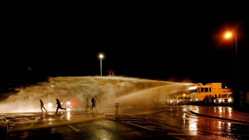 Rioters run as the police use a water cannon on the Springfield Road. Reuters