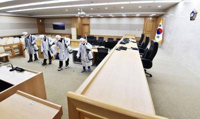 Workers wearing protective gear spray disinfectant as part of preventive measures against the spread of the COVID-19 coronavirus, in a courtroom at Suwon High Court in Suwon, South Korea.  AFP